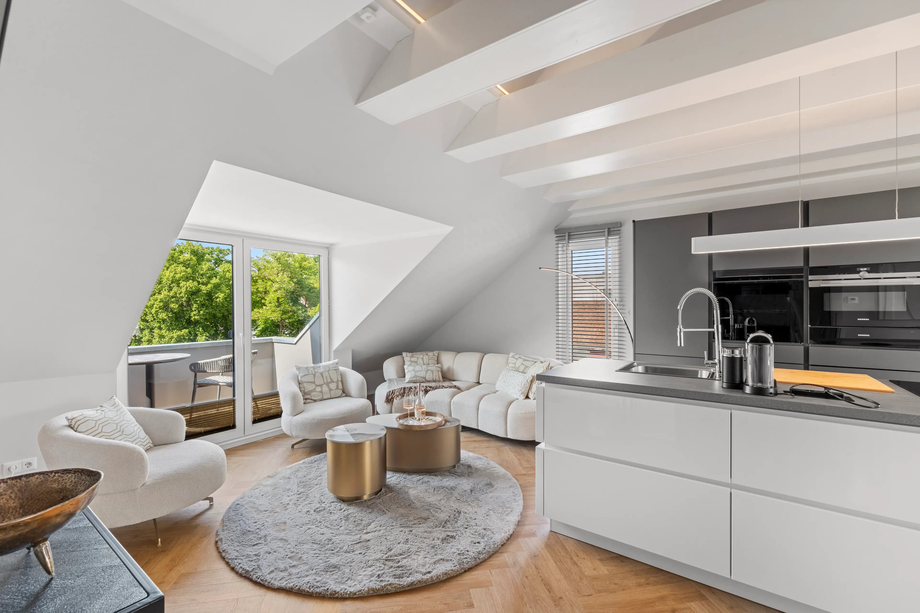 Wohnbereich des Penthouse mit Dachschräge und offener Küche